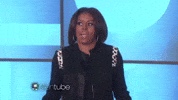 TV gif. Michelle Obama on The Ellen Show. She holds her hands outwards and shrugs her shoulders, looking like she doesn't have a clue what they're referring to.