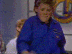 TV gif. A scene from Club Dance. A room full of kids dance around. A boy in a blue shirt stands in the middle of the crowd and wiggle his legs and shoulders, really feeling the music. 