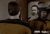 TV gif. Brent Spiner as Data and Michael Dorn as Worf in Star Trek: The Next Generation. They're both staring at the mirror at Data'a reflection, considering how they feel about his new beard, which he strokes.