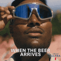 Sponsored gif. Man removes his sunglasses and looks upward with a concerned look on his face. Text reads, “When the beer arrives.”