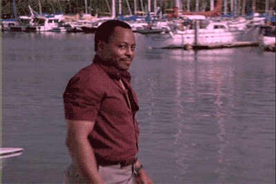 Video gif. A man turns and faces us with a pleased smile. He wipes his hands together as if a job has been done.