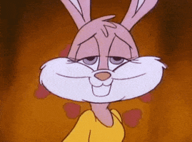 Cartoon gif. Against a gold background, cartoon Babs Bunny looks dreamily into the camera and brings her cheek to her shoulder. She bats her eyelashes. and her long ears flop down. She's surrounded by beating red cartoon hearts--she's in love!