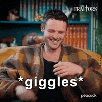 Sponsored gif. Traitors cast member Dylan Efron smiles and giggles. Text reads, “Giggles.”