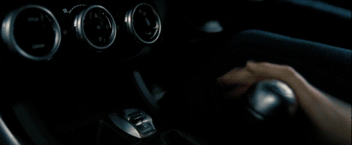 Movie gif. From "The Fast and The Furious," a close-up of a hand shifting gears and then a cut to a shot of a souped-up car passing another car inside of a tunnel, zooming toward us.