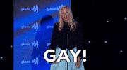Celebrity gif. Mira Sorvino at 2022 GLAAD Awards raises her fist and shouts "gay!"