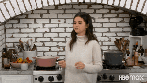 Reality TV gif. Selena Gomez in Selena and Chef stand in a kitchen and gives a chef's kiss as if she has tasted something perfect. 