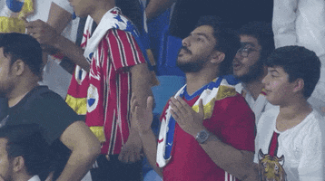 Sports gif. A sincere soccer fan prays in the stands, looking up like this is a huge moment for the team.