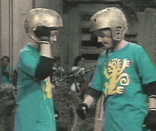 TV gif. Two young contestants on Legends of the Hidden Temple wear gold helmets and give each other a fist bump before a double high five. 