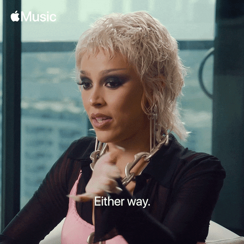 Celebrity gif. Doja Cat flicks her hand nonchalantly and says, "either way."