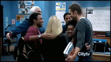 TV gif. Joel McHale as Jeff, Yvette Nicole Brown as Shirley, Danny Pudi as Abed, Donald Glover as Troy, Gillian Jacobs as Britta, Chevy Chase as Pierce in Community all come together in a big group hug inside a classroom.