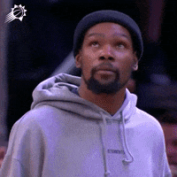 Sports gif. Kevin Durant of the Brooklyn Nets wearing a beanie and sweatshirt looks up and gives a casual salute like he's grateful or relieved about what just happened.