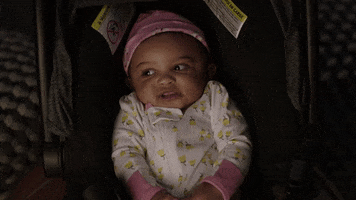 TV gif. Small baby in a carrier on 911 Lone star looks around with her shoulders up to her ears.