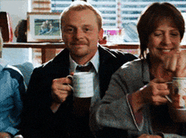 Movie gif. Simon Pegg as Shaun in Shaun of the Dead tips his mug to us and winks.