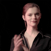 Video gif. Woman in black pajamas grins and claps slowly.