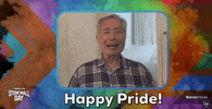 Celebrity gif. Video of George Takei saying "Happy Pride!" inset in a frame billowing with smoke overlaid with the progress pride flag. Logos in the corners: Stonewall Day and Warner Media.