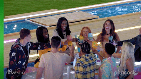 Reality TV gif. The cast from Love Island USA all toast and clink glasses, celebrating.