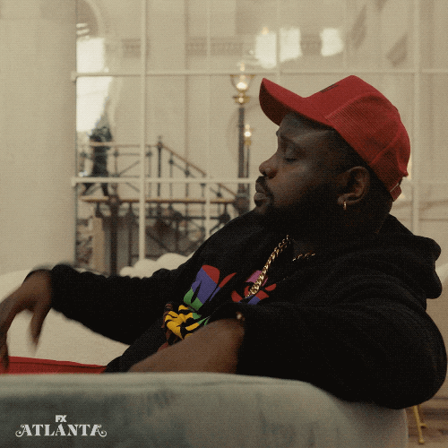 TV gif. Profile view of Brian Tyree Henry as Paper Boi on Atlanta, reclining against a sofa, kissing his fingertips and then fanning his fingers out in the air in front of him.