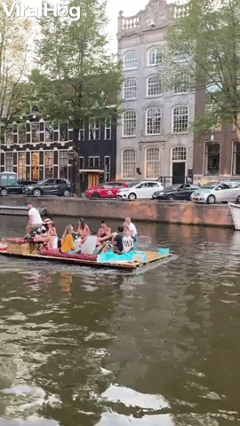 Guy Pushes Raft of People Down Canal