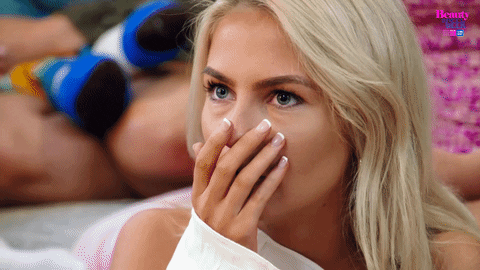 Reality TV gif. A scene from Beauty and the Geek Australia. A girl covers her mouth with her hand and then gasps in surprise. She smiles and holds her hands together. 