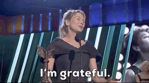 Celebrity gif. Smiling on stage, Renee Zellweger brings a hand to her stomach and says, “I'm grateful.”