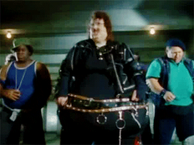 Music video gif. Weird Al Yankovic in "Fat" which is a parody of Michael Jackson's "Bad." Weird Al is dancing and hitting the pelvis thrust as he grabs the back of his head. 