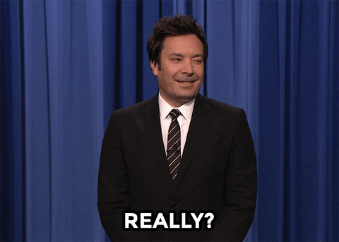Tonight Show gif. Jimmy Fallon stands in front of the curtain and looks doubtful, smiling and saying, "Really?!" while looking to the side for confirmation. 
