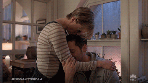 TV gif. From New Amsterdam, Lisa O'Hare as Georgia hugs Ryan Eggold as Max and kisses the top of his head.