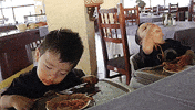 Video gif. Two young toddlers sit in high chairs with plates of spaghetti in front of them. Red Sauce is all over their faces. One kid bobs his head around and tries to keep his eyes open like he’s fighting sleep. The Other has his head all the way back and is shoveling noodles into his mouth.