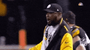 Sports gif. Mike Tomlin, coach of the Pittsburgh Steelers, rallies his team as they rush out onto the field ahead of him. He revs his arm back and whoops them on as they run.