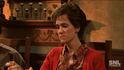 SNL gif. Kristen Wiig as Judith on Thanksgiving, sitting at a table, frowning with disdain at a forkful of food.