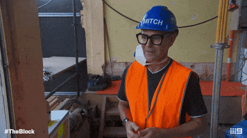 TV gif. The Block contestant Mitch, wearing a hard hat, lifts up both hands, crosses his fingers, and says, “fingers crossed!”