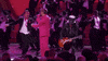 Oscars 2024 GIF. Ryan Gosling, dressed in a Barbie pink tuxedo and sunglasses, spins a background dancer Ken into his arms, who kisses him on the cheek, and spins out back into the chorus line.