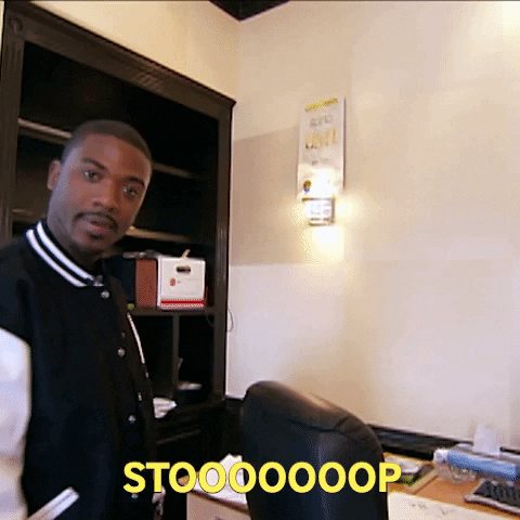 Celebrity gif. Ray J is in an empty office and he looks at us and says, "Stooooooop," while jokingly raising a hand in a backhanded slap position.