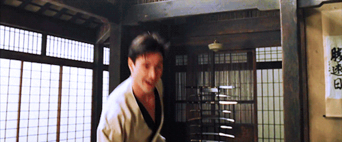Movie gif. Keanu Reeves as Neo in The Matrix. He's in a dojo wearing a karate uniform and has his fists up.
