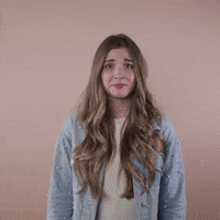 Reaction gif. A light-skinned woman with big eyes, shiny bronde hair, and cerebral palsy clutches her temple with a cringe and lowers out of frame.