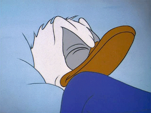 Cartoon gif. Donald Duck, asleep, wakes and rolls over to look over his shoulder and give a mean glare.