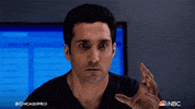 TV gif. Dominic Rains as Dr. Crockett Marcel on Chicago Med looks at someone with intense fear. He lowers his hand and stands up straight.