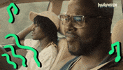 Sponsored gif. Actors Lupita Nyong'o and Winston Duke in the movie “Us” bop their heads to music while driving in a car.