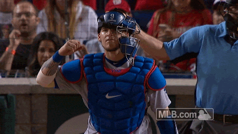 Sports gif. Yasmani Grandal from the LA Dodgers stands up as he watches a play. He yells out with pleasure as the play is successful and does a fist pump in joy.