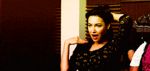 TV gif. Naya Rivera as Santana Lopez in Glee, holding her hair back and fanning herself off like she's swooning over someone.