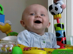 Video gif. A smiling baby jerks as if scared and its eyes grow wide as it stares in shock. 