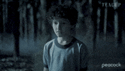 Sponsored gif. Video of Caleb Dolden as Arlo Chenoweth on Teacup in spooky fog, turning to see and reveal a man stumbling out of the woods head drooped dramatically, perhaps a zombie. The Peacock logo in the bottom right hand corner.