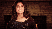 Celebrity gif. Selena Gomez smiles at us and holds two thumbs up.