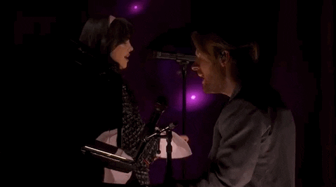Oscars 2024 GIF. Billie Eilish and Finneas performing "What Was I Made For" on stage at the Oscars. Finneas is on the piano and Eilish stands next to him. The camera angle films from Finneas's side, and Finneas is in the foreground while Eilish sings in the background. 
