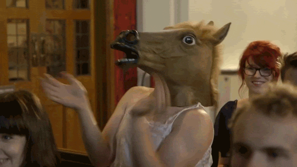 Video gif. A woman wearing a horse head mask claps eagerly and gives a big thumbs up as the mask flaps around.