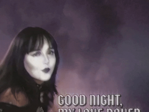 Video gif. A young goth woman uses her hands as wings and flaps in, saying, "Goodnight my love raven," and flaps out, with lightning streaking the sky in the back.