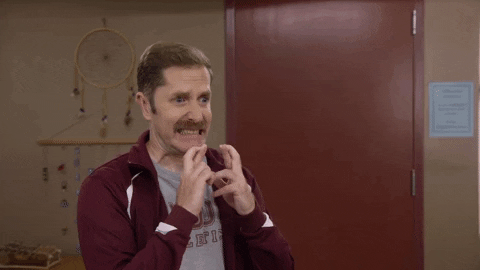 TV gif. Crossing his fingers on both hands, a short-haired man with a moustache nervously looks offscreen.