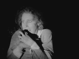 Movie gif. Brigitte Helm as Maria in 1927 film Metropolis trembles terribly in fear, and her clenched hands claw at her face as her head bends back while she screams.