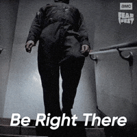 Sponsored gif. Michael Myers from Halloween walks slowly down a stairwell. In the upper right corner is the AMC Fear Fest logo. Text reads, “Be right there.”