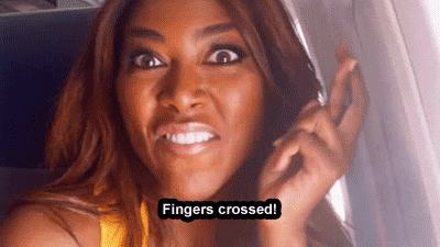 Reality TV gif. Kenya Moore from Real Housewives of Atlanta is on a plane and is recording herself. She crosses her fingers and looks hopeful.
